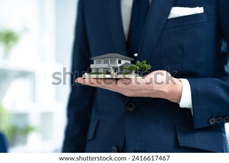 Man's hand holding miniature building