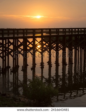 wooden bridge beside the river, at sunset, photo of the bridge silhouette.