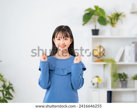 Asian little girl showing fist pump in room. Royalty-Free Stock Photo #2416646255
