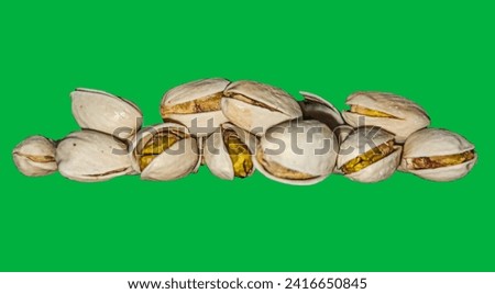 Freshly baked pistachios on a vibrant green backdrop. Perfect for food blogs and wellness content. Irresistible and versatile stock photo.