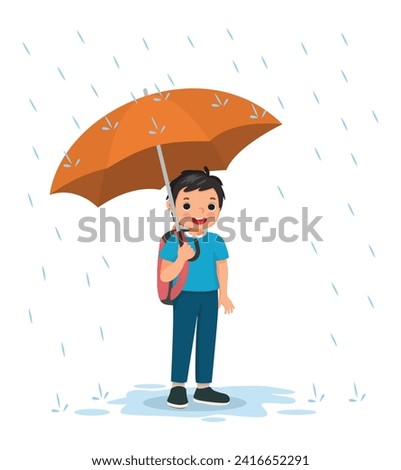 Happy little boy student with backpack holding umbrella in the rain