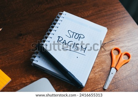 photograph of notebook with phrase "stop racism" on a table. 