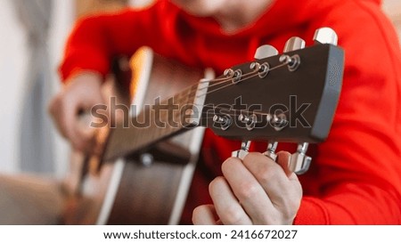 Instrument tuning. Professional guitarist. Creative performer man hands fingers adjusting pegs and gears on headstock music equipment indoors. Royalty-Free Stock Photo #2416672027