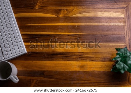Picture of a white coffee mug placed on a wooden table with a keyboard and a small plant.