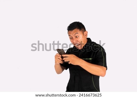 Mature Asian man showing excited gesture while looking to his mobile phone