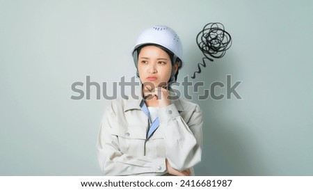 A depressed woman wearing work clothes. Engineer. Construction worker. Repair shop. Electrician. Royalty-Free Stock Photo #2416681987