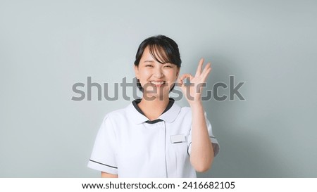 A woman wearing a white coat showing a circle hand sign. Nurse. Clinic staff.