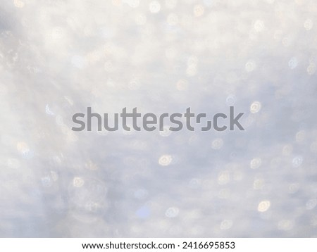 Artistic, shiny, purposely blurred background with white and colorful bokeh effect of snow in sunlight. Photographic bokeh effect