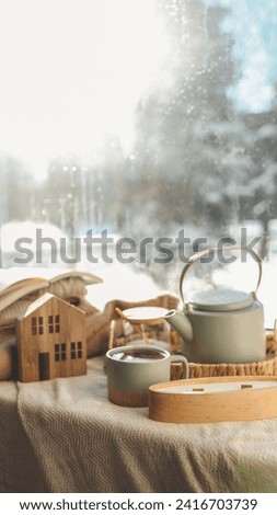 Cozy winter home interior, candle, tea and teapot on the windowsill.