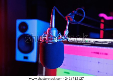 Professional condenser studio microphone on the background of an audio mixer and monitor in a recording studio