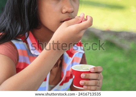 Traveling woman eating ice cream with a spoon in a cup at Ice Cream