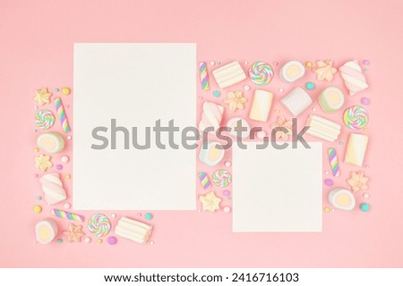 Set of two blank white cards on cute pastel pink kawaii background with frame of sweet candies, meringue and marshmallows . Flat lay, top view, copy space. Beautiful childlike design template