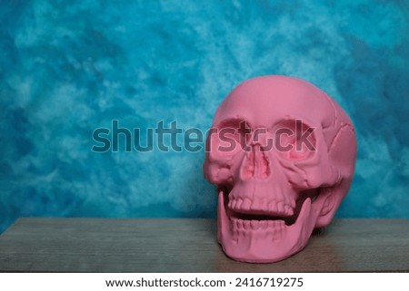 Pink skull on a blue background. Halloween concept. Copy space.