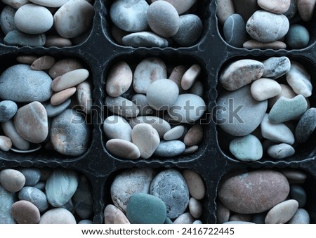 Pattern Of Symmetrical Partitions Of Cellular Tray Full Of Decorative Stones Royalty-Free Stock Photo #2416722445