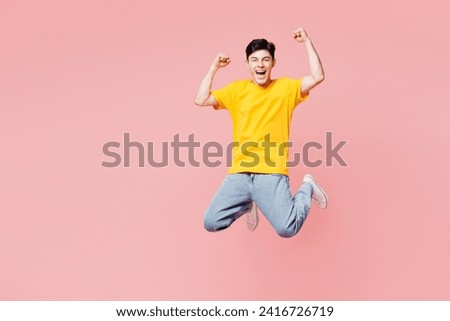 Full body overjoyed excited cool fun young man he wearing yellow t-shirt casual clothes jump high do winner gesture isolated on plain pastel light pink background studio portrait. Lifestyle concept Royalty-Free Stock Photo #2416726719