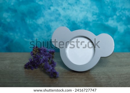 picture frame and purple flower on wooden table with blue background. mock up