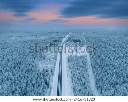 Aerial view of beautiful winter landscape and road in Lapland during sunset. Royalty-Free Stock Photo #2416731323