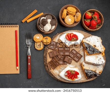 The image depicts a table with a variety of food items including baked goods, desserts, fruits, and bread. The spread also includes utensils such as forks and plates.