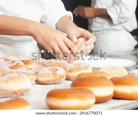 The image shows a person making donuts indoors. Royalty-Free Stock Photo #2416770071