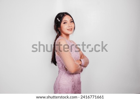 An attractive Asian woman wearing pink dress is smiling to the camera, isolated by white background.