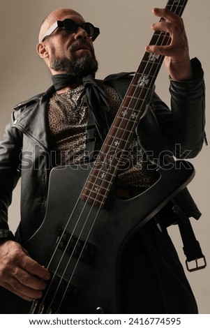 Rock musician. A man with black electric guitar poses at the studio.Vertical.