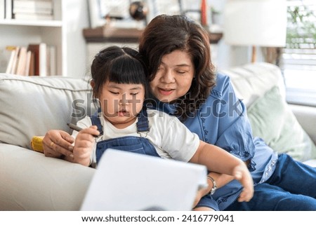 Portrait of happy love asian grandmother and asian little cute girl hug and enjoy relax on bed at home.Young girl with their laughing grandparents smiling together.Family and togetherness