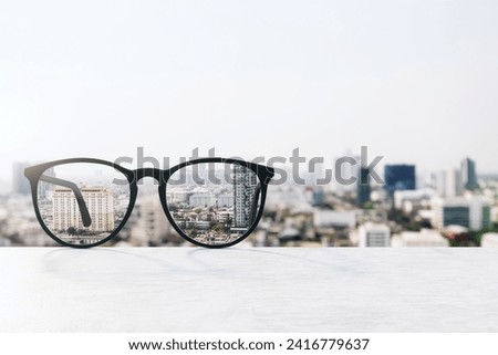 Conceptual image of glasses focusing on urban landscape, clarity in vision and perception Royalty-Free Stock Photo #2416779637