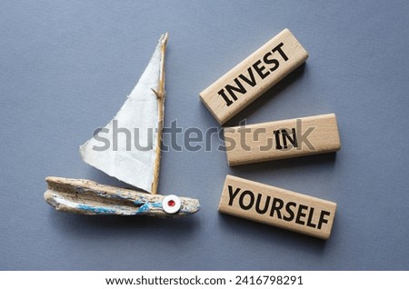 Invest in Yourself symbol. Concept words Invest in Yourself on wooden blocks. Beautiful grey background with boat. Business and Invest in Yourself concept. Copy space.