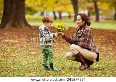 Cute little boy giving flowers to his mother