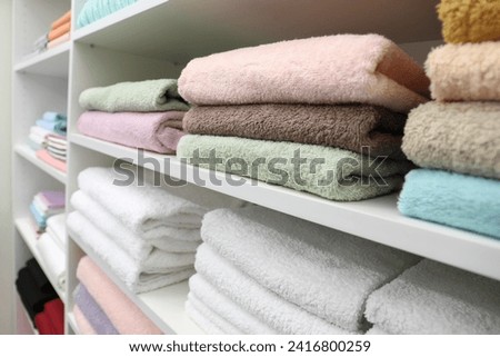 Different terry towels on shelves in linen shop Royalty-Free Stock Photo #2416800259