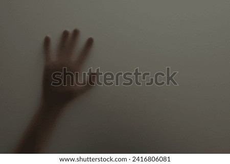 Silhouette of creepy ghost behind glass against grey background, closeup. Space for text