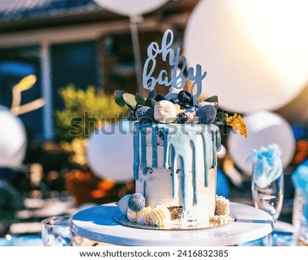 The image is a cake with decorations. It may be used for birthdays, weddings, or other events. The cake is displayed on a table outdoors.