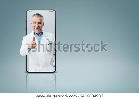Professional doctor in a smartphone giving a thumbs up videocall and smiling, online doctor and telemedicine service concept Royalty-Free Stock Photo #2416834983