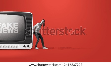 Woman pushing away an old television broadcasting fake news: fight disinformation concept Royalty-Free Stock Photo #2416837927
