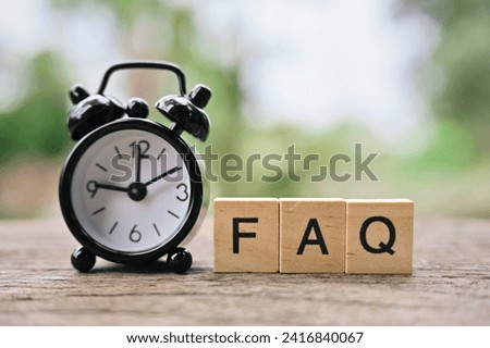 close up FAQ wooden text block and small alarm clock on wood table, Frequently Asked Questions
