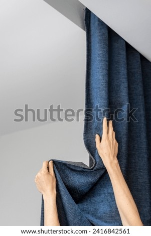 Vertical shot of female fixing the curtains. Cropped shot of woman hands drapes folds on fabric and closed window blinds. Shutters installed in hidden guide rail on plasterboard ceiling Royalty-Free Stock Photo #2416842561