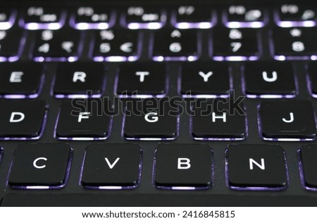 Glowing neon blue laptop keyboard. Close-up.