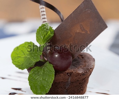 The image is a chocolate bar with a cherry on top. It is placed on a table, and it can be assumed that it is a dessert.