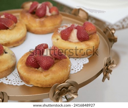 The image features a group of pastries topped with raspberries. The pastries appear to be sweet and baked, making them a delicious dessert or snack option. The presence of berries adds a fruity