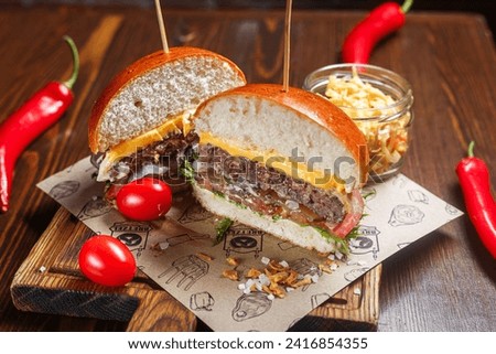 Bacon burger with beef, cheese and vegetables on a wooden background
