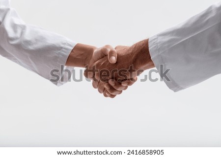 Male and female medical professionals demonstrate unity and shared purpose through a firm handshake Royalty-Free Stock Photo #2416858905
