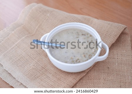 Mung Bean Porridge or Bubur Kacang Hijau, Indonesian dessert porridge of mung beans with coconut milk, pandan leaf and ginger. Served in bowl.