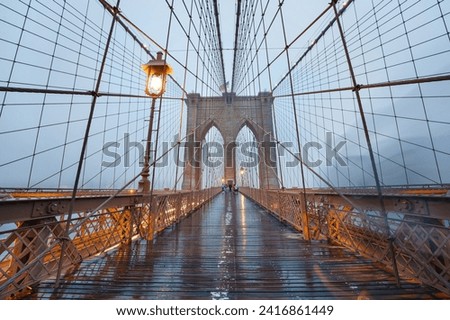  Brooklyn Bridge on rainy night in New York City USA. Skyscrapers in the fog.