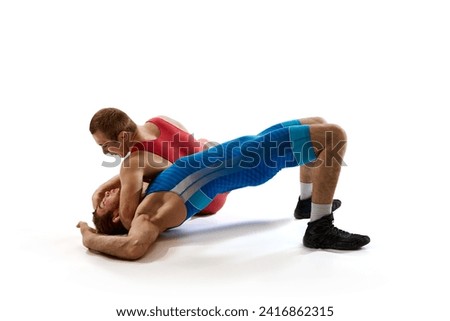 Two strong and competitive man in red and blue sportwear fighting in action against white studio background. Concept of fair wrestling, championship, win competition, training, power and strength.