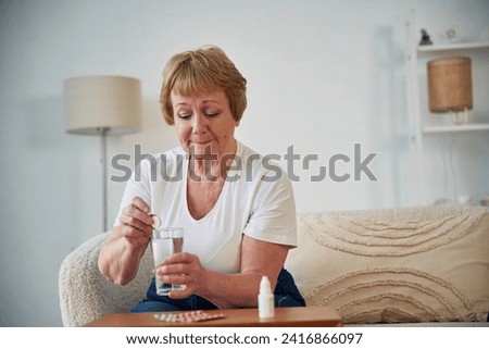 Self medicate. Taking medicine. Senior elderly woman is at home in the living room. Royalty-Free Stock Photo #2416866097