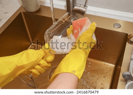 Young woman in yellow rubber gloves washing dishes with a sponge	