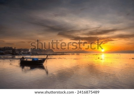 Morning sunrise with traditional long tail boats and fishing village background in southern Thailand