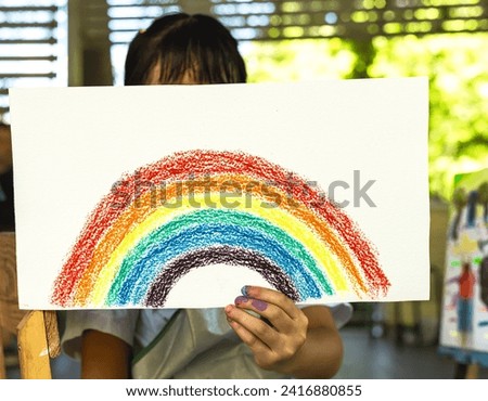 Close up artist girl holding colorful rainbow crayon drawing