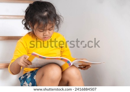  little girl happily reading a storybook at home