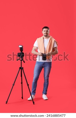 Male photographer with professional cameras on red background
